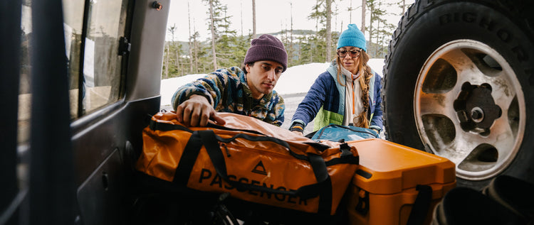 People unpacking bags from the back of a truck, in the mountains