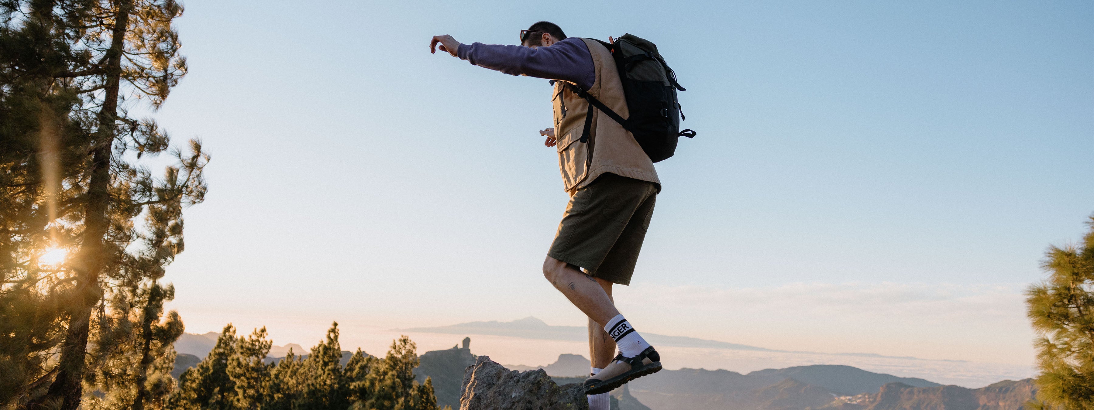 Person hiking with a backpack on a mountain trail at sunset