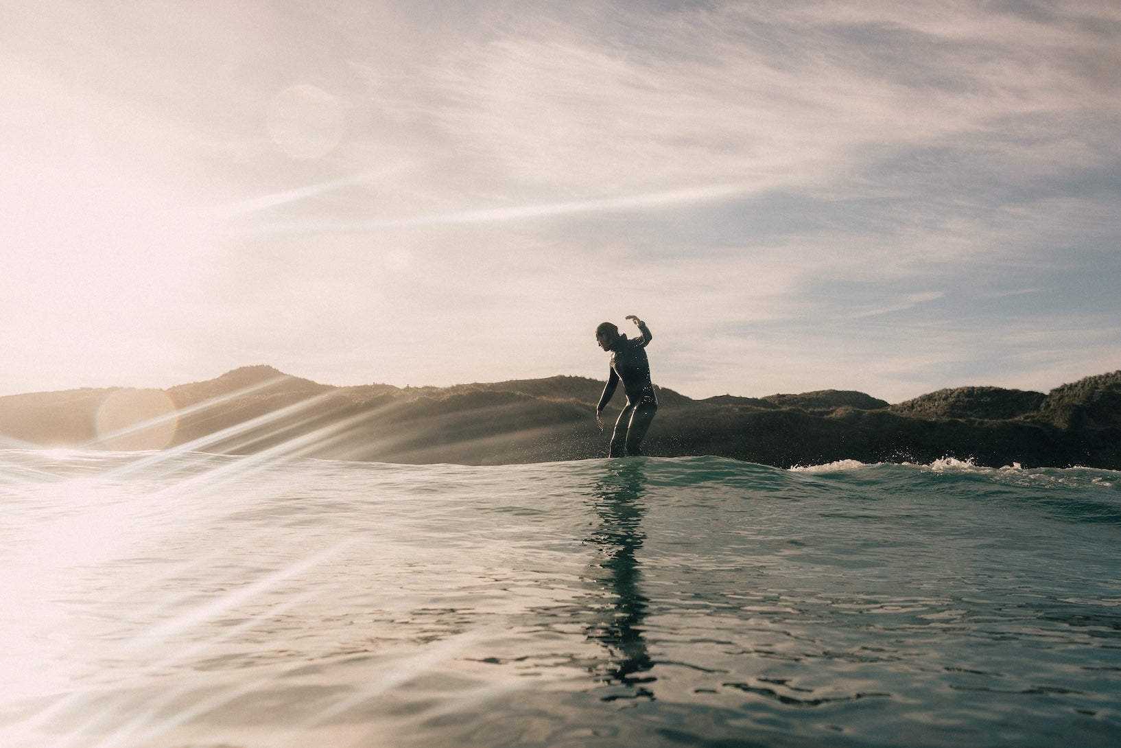 Person surfing in the water with a scenic background